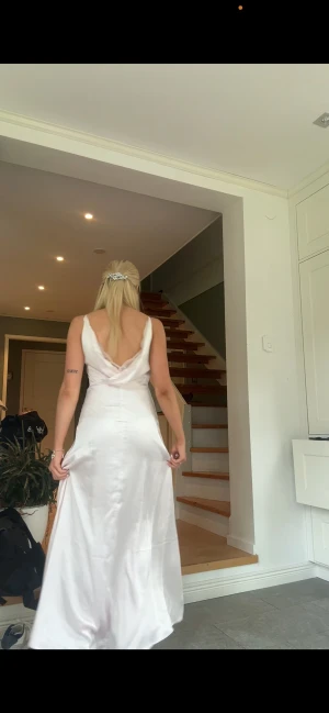 Ljusrosa balklänning - Säljer en elegant ljusrosa långklänning i satin med smala axelband, slits på sidan och snygg omlott-detalj i ryggen. Klänningen har en mjuk glans och följsam passform som ger en lyxig känsla. Perfekt för bal eller student! 💫