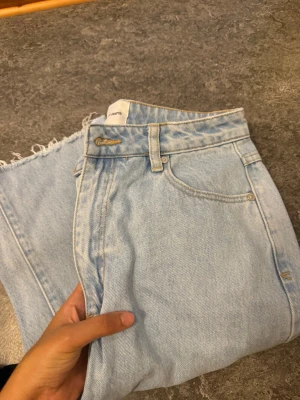 Abrand Jeans High Straight ljusblå - Säljer ett par ljusblå jeans från Abrand Jeans i modellen High Straight. Byxorna har hög midja, raka ben och råa, fransiga benslut för en chill vibe. Klassisk femficksdesign och tillverkade i jeansmaterial med ljus tvätt.