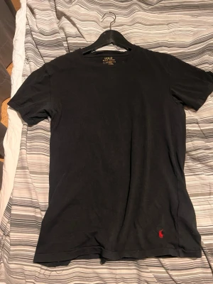 Svart t-shirt från Polo Ralph Lauren - Svart t-shirt från Polo Ralph Lauren i bomull med klassisk passform. T-shirten har korta ärmar och en röd broderad logga nertill. Enkel och stilren design som funkar till allt. Sitter som S/M. Köptes från zalando