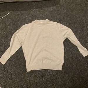 Ljusgrå polotröja från Zara - Säljer en stilren ljusgrå polotröja från Zara i storlek 164. Tröjan har lång ärm, ribbad krage och är gjord i mjukt material som känns skönt mot huden. Perfekt för dig som gillar enkel och clean stil.