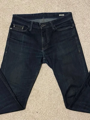 Jeans från Calvin Klein - Snygga mörkblå jeans från Calvin Klein i modellen slim straight. Klassisk femficksdesign med coola sömmar på bakfickorna och diskret logopatch i skinn på linningen. Jeansen är gjorda i slitstarkt bomullsmaterial och har en rak passform som sitter schysst.