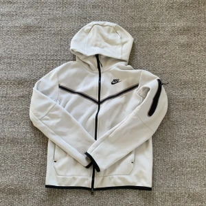 Vit hoodiejacka från Nike med svarta detaljer - Säljer en vit Nike tech fleecetröja, köpt på footlocker i Stockholm 