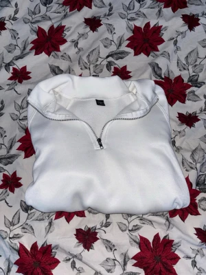 Vit half zip sweatshirt från H&M - Säljer en fräsch vit sweatshirt från H&M med half zip-dragkedja och hög krage. Tröjan har långa ärmar och ribbade muddar vid ärmslut och nederkant. Perfekt för chill dagar och enkel att matcha med jeans eller mjukis.