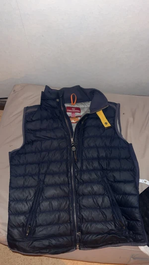 Mörkblå dunväst från Parajumpers XS - Säljer en mörkblå dunväst från Parajumpers i storlek XS. Västen har quiltad design, två dragkedjefickor och en gul detalj vid kragen. Perfekt för lager-på-lager och har en snygg, sportig look med hög krage och dubbla dragkedjor. Skriv ifall ni har några frågor 😉priset går att diskuteras!