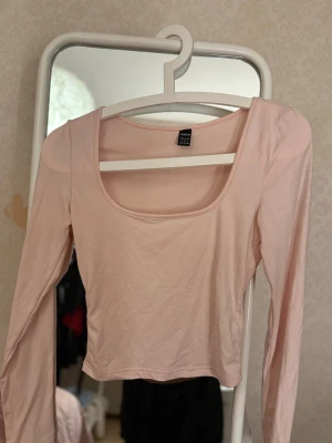 Ljusrosa långärmad topp  - Säljer en ljusrosa långärmad topp med rundad, djup halsringning. 