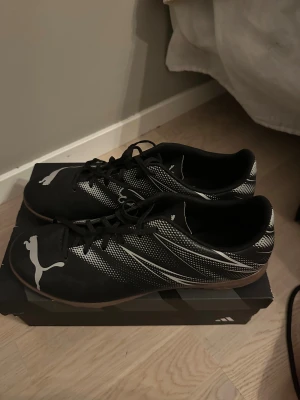 Svarta Puma inomhusfotbollsskor - Säljer ett par svarta fotbollsskor från Puma. Perfekt för futsal eller idrott/gym. Knappt använda bara enstaka gånger. Storlek 46