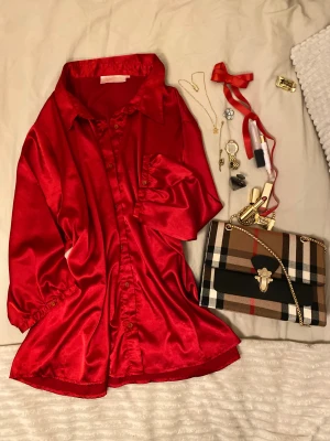 Röd Silkes lik skjorta från Cellbes of Sweden - Silkes lik skjorta med glansig finish och klassisk krage. Skjortan har mellan långa ärmar med knapp,  knäppning hela vägen framtill. Materialet är mjukt och har en lyxig satinlook som verkligen sticker ut.❤️❣️ Det är en dam skjorta men funkar utmärkt till män som bild exempelet. 🤩Jag äger inte modell bilderna 4&5 , det bara exepmpel hur ni kan styla plagget. Tröjan är väldigt stor! . Hör gärna av dig vid frågor eller snabb affär🙂🤝