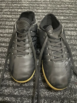Umbro futsalsskor - Svarta futsalskor från Umbro i bra skick men har en liten missfärgning på sidan av vänsta skon. De är unisex och i storlek 35.