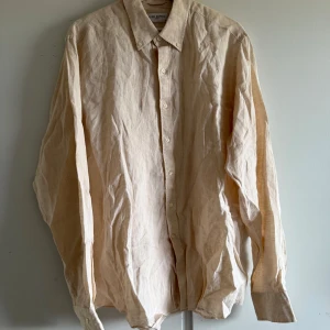 Beige linneskjorta från John Henric - Säljer en stilren beige skjorta i linne från John Henric. Skjortan har klassisk krage, knäppning framtill och långa ärmar. Perfekt för en avslappnad men ändå uppklädd look.