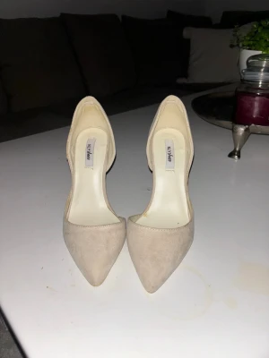 Beige pumps med spetsig tå från NLY Shoes - Snygga pumps i beige mocka-look från NLY Shoes. Skorna har spetsig tå och hög klack som ger en elegant siluett. Perfekta för dig som vill ha en stilren och klassisk look. Materialet känns mjukt och lyxigt. Använt ett fåtal gånger och är väldigt bekväma, säljer pga för små. 