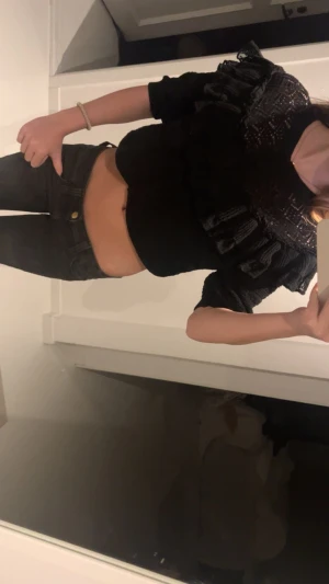 Svart croppad blus med volang från Zara - Säljer en svart croppad blus från Zara med snygga volanger och spets. Den passar till det mesta och går även att ha linne under! 