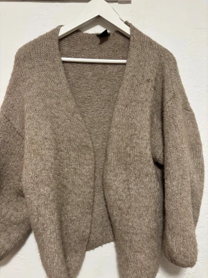 Beige stickad kofta från Lindex - Mysig beige stickad kofta från Lindex i storlek M/L. Koftan har en loose passform, långärmade ärmar och är öppen framtill utan knappar. Perfekt för lager-på-lager och chill dagar. Materialet är mjukt och ger en skön känsla.