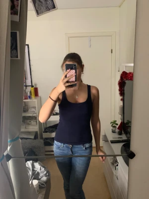 Mörkblå linnetopp💙 - Säljer en enkel och stilren mörkblå linnetopp med breda axelband. Toppen är figurnära och har en klassisk rund halsringning. Perfekt att matcha med jeans eller shorts för en avslappnad look. Materialet är mjukt och bekvämt bomull.❣️