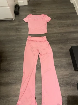 Rosa croppad topp med kort ärm - Säljer en ljusrosa croppad topp med korta ärmar och rundad halsringning. Toppens material är mjukt och stretchigt, perfekt för dig som gillar bekväma och snygga plagg. Passar dig som vill ha en enkel men ändå trendig look.