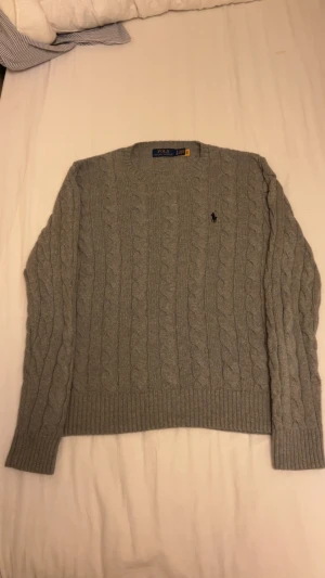 Polo Ralph Lauren stickad  - Säljer en grå kabelstickad tröja från Polo Ralph Lauren i storlek S helt oanvänd!!!