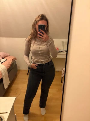 Mörkgrå raka jeans - Säljer ett par mörkgrå jeans med rak passform och hög midja. Klassisk femficksmodell med knapp och dragkedja framtill. Jeansen är tillverkade i jeansmaterial och har en stilren look som funkar till många olika outfits. Nypris 400kr