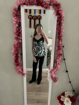 Grön och vit mönstrad linnetopp med spets - Säljer en snygg linnetopp från Amisu i storlek XS. Toppen har ett grönt och vitt abstrakt mönster, tunna axelband och dekorativ mörkgrön spets vid v-ringningen. Materialet är glansigt och känns lyxigt mot huden. Perfekt för dig som gillar unika detaljer och coola prints.