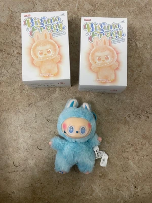 Blå fluffig väst med kaninöron - Säljer en gullig blå väst med fluffigt material och söta kaninöron från Pop Mart. Västen har en rund form och är tillverkad i syntetiskt pälsliknande tyg. Perfekt för dig som gillar unika och lekfulla plagg med extra detaljer.