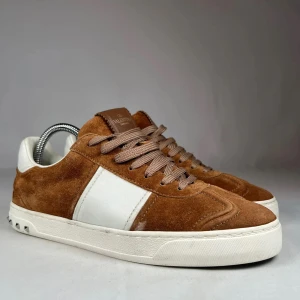 Valentino Garavani bruna sneakers mocka - Snygga sneakers från Valentino Garavani i brun mocka för 3499kr . Skorna har bruna snören, vit panel på sidan och små nitar på hälen. Skorna är också i storlek 41.