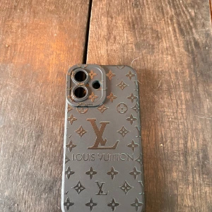 Louis Vuitton iPhone 16 skal - Elegant Louis Vuitton mobilskal för iPhone 16 med klassiskt LV-mönster. Skalet är i mycket gott skick utan synligt slitage och ger både stil och skydd till din telefon. Perfekt passform för kameran och knappar.