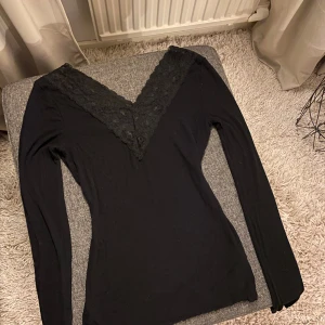Svart långärmad topp med spets - Svart långärmad topp med v-ringning. Toppen är tunn och skön. Storlek XS.