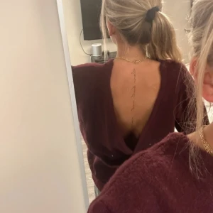  stickad tröja med öppen rygg -  stickad tröja med en djup öppen rygg. Tröjan har en loose passform och är perfekt för dig som vill ha något både bekvämt och snyggt. Tröjan är vinröd med en lila underton.  Materialet är mjukt och passar bra till höst och vinter.
