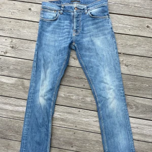Nudie Jeans  - Snygga ljusblå Nudie Jeans Grim Tim Pale Shelter med klassisk femficksdesign och raka ben. Tillverkade av 98% ekologisk bomull och 2% elastan för skön stretch. Faded detaljer och kontrastsömmar ger en cool vintagekänsla.
