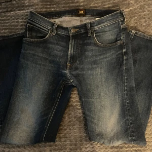Lee Daren Zip Fly jeans blå W30 L30 - Snygga Lee Daren Zip Fly jeans i klassisk blå tvätt med lätt slitning. Modellen har raka ben, fem fickor och dragkedja i gylfen. Jeansen är tillverkade i bomull och har kontrastsömmar samt Lee-logga på bakfickan. Perfekt passform för dig som gillar stilrena jeans.