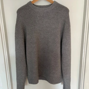 Grå stickad tröja från Zara - Mysig grå stickad tröja från Zara i storlek L. Tröjan har en klassisk rund halsringning, ribbade muddar och är långärmad. Perfekt för lager-på-lager och chill dagar. Enkel och stilren design som funkar till det mesta. Slim fit