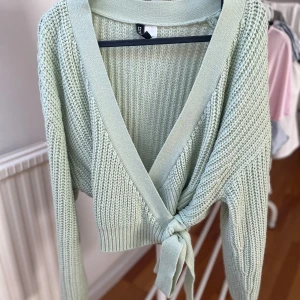 Ljusgrön stickad omlottkofta  - Superfin ljusgrön stickad omlottkofta från Hm. Koftan har lång ärm, bred ribbad kant och knyt framtill. 