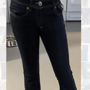 Mörkblå jeans med raka ben - Snygga mörkblå jeans med raka ben och kontrastsömmar. Klassisk femficksmodell med lock och knapp på bakfickorna. Hög midja och silverfärgade knappar. Perfekta till sneakers eller boots.