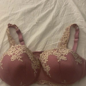 Intimissmi bh - Säljer en romantisk rosa blus med vackra broderade spetsdetaljer i beige. Toppen har en feminin form med axelband och dekorativa spetsmönster över kuporna och längs kanterna. Perfekt för dig som gillar detaljer och mjuka färger.