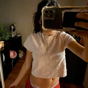 Ljusrosa pärlprydd topp Divided - Supersöt ljusrosa croppad topp från Divided, dekorerad med pärlor över hela framsidan. Toppen har korta ärmar och rund halsringning, perfekt för dig som gillar en gullig och trendig stil.