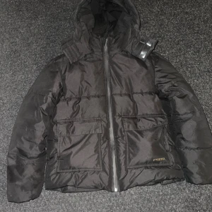 Svart pufferjacka från Pegador M - Säljer min svarta Pegador-pufferjacka i storlek M. Nypris 1800 kr. Använd endast en vinter, men ser fortfarande helt perfekt ut – inga fläckar eller skador! 😍 	•	Praktisk två-i-ett-ficka på båda sidor – sidofickorna är varma och sköna att ha händerna i under kalla vinterdagar. 	•	När jackan blir lite blöt framträder ett snyggt mönster med “PGDR” – en unik detalj som verkligen sticker ut. 	•	Säljer eftersom jag fick en annan jacka i födelsedagspresent – annars skulle jag aldrig sälja denna!