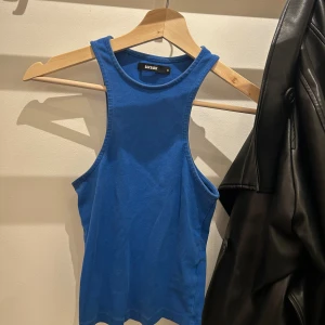 Blå linnetopp  - Säljer en enkel och snygg blå linnetopp från Bik Bok i storlek M. Toppen har en rak och ärmlös design med rund halsringning och är gjord i mjuk bomull. Perfekt att styla med jeans eller shorts för en chill look.