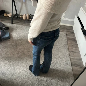 Blå jeans med bootcut - Snygga blå jeans med klassisk bootcut och utsvängda ben. Jeansen har en mörk tvätt och tydliga sömmar, samt bakfickor med enkel design. Perfekta för dig som gillar en tidlös och avslappnad stil.