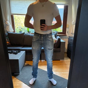 Blåa Dondup Jeans - Säljer ett par blå jeans från Dondup, modell George. Jeansen har snygga slitningar och en tvättad look, klassiska fem fickor och knappgylf. Tillverkade i bomull med en riktigt skön passform. Jag är 178 och väger 66kg