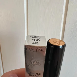 Lancôme L'Absolu Rouge 186 Idole Matte - Lancôme L'Absolu Rouge i nyansen 186 Idole Matte är ett ikoniskt läppstift i en intensivt röd färg med matt finish. Snygg svart och guldig hylsa med rosdetalj på toppen. Perfekt för dig som vill ha en klassisk, djärv look med lyxig känsla. Helt ny i förpackning.