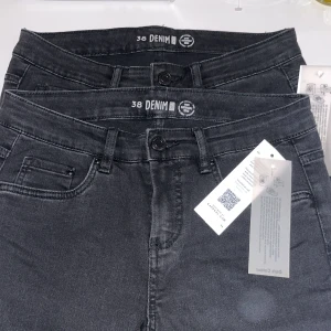 Svarta skinny jeans med dragkedja - Svarta skinny jeans från Denim i storlek 38. Jeansen har klassisk femficksdesign, bälteshällor och dragkedja vid benslut för en extra cool detalj. Tillverkade i stretchigt jeanstyg för en tight och bekväm passform. 100kr styck eller 150kr för båda