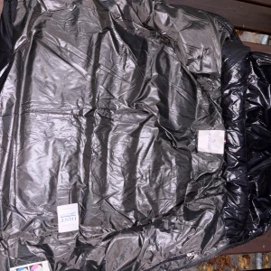 Svart Moncler pufferjacka med stor logga - Säljer en svart pufferjacka från Moncler med glansig finish och stor vit broderad Moncler-logga på ärmen. Jackan har klassisk Moncler-komik på insidan och märkets ikoniska patch. Perfekt för dig som vill sticka ut med en lyxig vinterjacka.