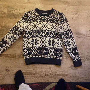 Svartvit stickad tröja från Kappahl - Säljer en svartvit stickad tröja från Kappahl med snyggt vintermönster och stjärnor. Tröjan har rund hals och långa ärmar, perfekt för kalla dagar. Mönstret är inspirerat av klassiska nordiska motiv och ger en riktigt mysig vibe.