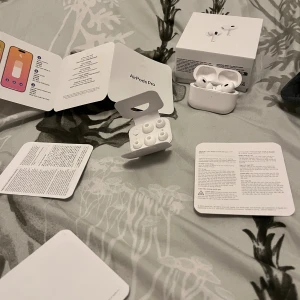 AirPods Pro - Apple AirPods Pro i mycket fint skick, komplett med originalförpackning, extra öronkuddar och manualer. Aktiv brusreducering, transparensläge och hörselanpassning. Perfekt för musik, samtal och träning. Inga synliga defekter eller slitage.