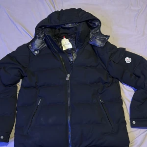 Monclere Flannel Down Jacket black. - Bäst skick på marknaden. Leverar samma dag som betalning. Priset är ej hugget i sten. En riktigt snygg vinterjacka i storlek 2 som då motsvara M riktigt snygg och varm och funkar perfekt. Utanpå är det ett fleece material som hjälper att både se bättre ut och bli varmare. Luvan går att ta bort och man kan scanna jackans märke. 