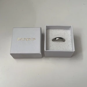 Klassisk silverring från Syster P - En stilren och tidlös oanvänd silverring från Syster P. Ringen har en slät, rundad form och kommer i original ask. Perfekt för dig som gillar minimalistiska smycken med en elegant touch. 🥰🔥| priset är inte slaget i sten och kan diskuteras. Frakt betalar kunden 🙃