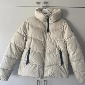 Beige pufferjacket från Everest - Jag säljer en fin Everest dunjacka i mycket bra skick. Köpt för 1000kr och använd max 10 gånger. Inga hål eller fläckar 😊. Säljer då den inte längre kommer till användning. Den är i en jätte fin vit/beige färg och ett svart Everest märke på vänster arm. Den är håller värmen väldigt bra. Storlek 36. Hör av dig vid fler frågor 😉