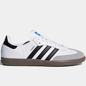 Adidas Samba vita och svarta sneakers - Klassiska Adidas Samba sneakers i vitt skinn med svarta ränder och grå mockadetaljer vid tån. Snygg gummisula och snörning framtill. Perfekta för dig som gillar retrostil och streetwear. Skicket är typ 9 av 10. Mer bilder fås privat! 