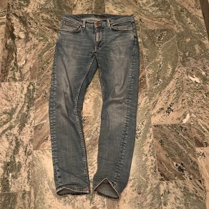 Nudie jeans Lean Dean 32/32 - Sjukt snygga nudie jeans i storlek 32/32. Det är en riktigt snygg ljusblå tvätt på jeansen. Modellen är lean dean. Jeansen har en liten slitning vid högre knät(bild 4) 