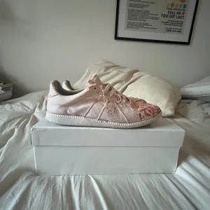 Maison margiela skor med färgskvätt - Maison Margiela sneakers i ljusrosa med röd och vit splatter-effekt över hela skon. Klassisk rund tå, snörning och platt sula. Snygg och unik design. Bra skick knappt använda