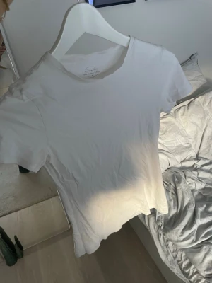 Vit t-shirt från Intimissimi i Supima-bomull - Klassisk vit t-shirt från Intimissimi i 100% Ultrafresh Supima-bomull. Modellen är figurnära med rund hals och korta ärmar. Perfekt basic-plagg med mjukt och lyxigt material som känns skönt mot huden. Hör av er för fler frågor💗