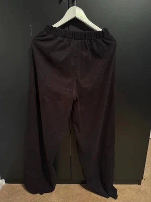 Svarta manchesterbyxor med resårmidja - Säljer ett par svarta manchesterbyxor med breda ben och skön resår i midjan. Byxorna har en loose passform och är perfekta för dig som gillar en avslappnad stil. Materialet är mjukt och ger en cool retrovibe.